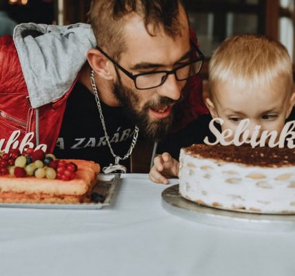 A joyful birthday scene with a father and child. Cakes adorned with decorations and age markers.